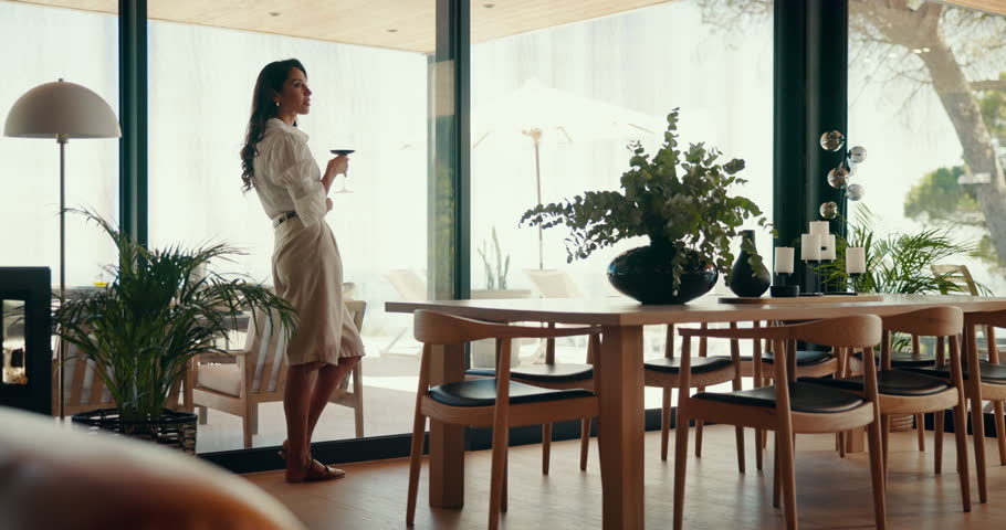 Peace, woman and drink wine in home for relax, thinking or calm by window view for reflection. Alcohol glass, living room and person with beverage, dream or remember memory on weekend in luxury house