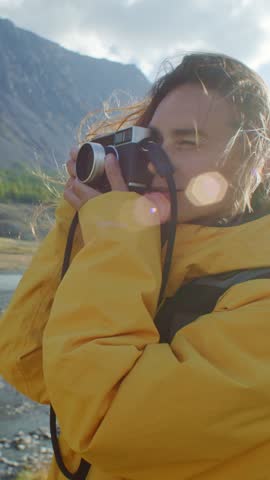Female photographer taking pictures with vintage camera of a stunning river landscape under vibrant skies