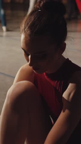 A dancer reflects while preparing her ballet shoes, showcasing grace