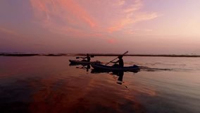 Silhouette Couple friends canoeing on a wooden canoe during a colorful sunny sunset. Cloudy Sky Composite. - Powered by Shutterstock - Get 15% off with code: PIKWIZARD15