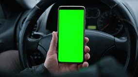 Man using phone with blank green background while driving. Road safety. Automotive technologies. GPS navigation. Mobile applications for drivers. Using gadgets while driving. Smartphone chroma key - Powered by Shutterstock - Get 15% off with code: PIKWIZARD15