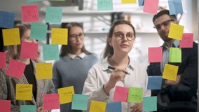 Young Business Team Brainstorming. Business Woman Draws a Graph On Glass Wall With Stickers. Colleagues Approve. Business Success Concept - Powered by Shutterstock - Get 15% off with code: PIKWIZARD15