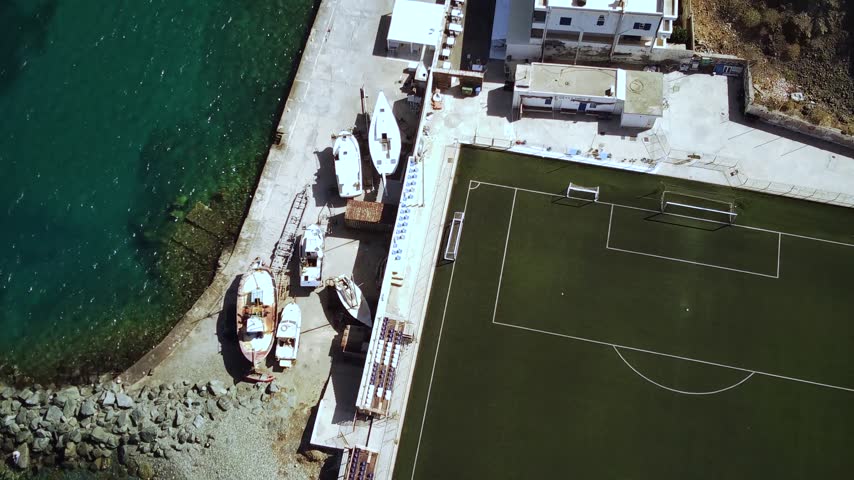 A drone footage of Tinos Municipal Stadium and Coastal buildings on a sunny day in Tinos, Tinos Island, Greece