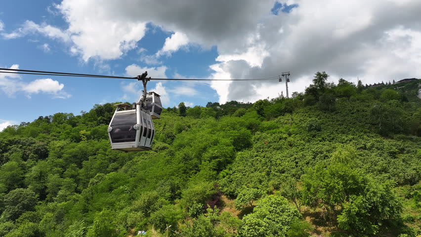 Aerial view of a cable car on a green hill with the city of Ordu and coastline in the background, oe01