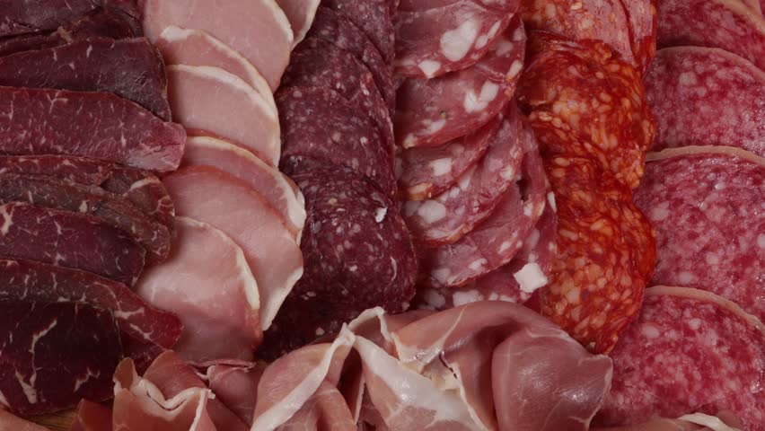 Selection of ham, salami cold meat on board food zoom top view