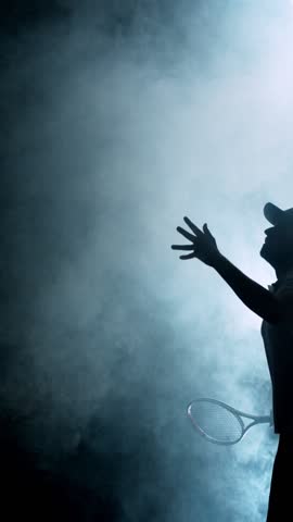 Super Slow Motion of Tennis Player Silhouette Hitting Ball. Smoke Effect Around, Black Background. Filmed on High Speed Cinema Camera, 1000fps. Vertical Aspect Ratio.