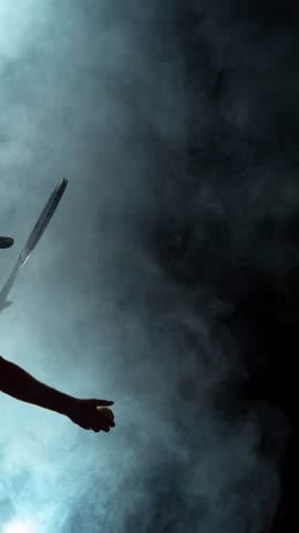Super Slow Motion of Tennis Player Silhouette Hitting Ball. Smoke Effect Around, Black Background. Filmed on High Speed Cinema Camera, 1000fps. Vertical Aspect Ratio.