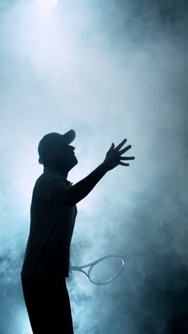 Super Slow Motion of Tennis Player Silhouette Hitting Ball. Smoke Effect Around, Black Background. Filmed on High Speed Cinema Camera, 1000fps. Vertical Aspect Ratio.