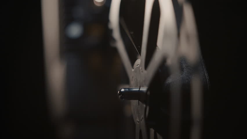Close ups of a vintage 8MM projector spools moving and playing film 