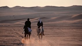 A Saudi couple rides majestic Arabian horses through the desert, bathed in the golden sunset. They skillfully guide their horses, urging them to rise on their hind legs - Powered by Shutterstock - Get 15% off with code: PIKWIZARD15