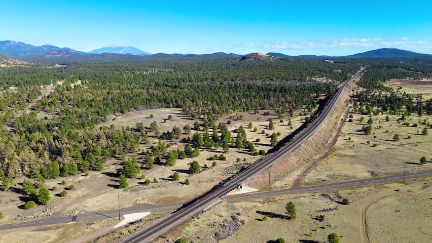 A BNSF Freight Train Passes Through Williams, Arizona, with Flagstaff's San Francisco Mountain Peaks In View, near the borders with California and Utah, along old Route 66.