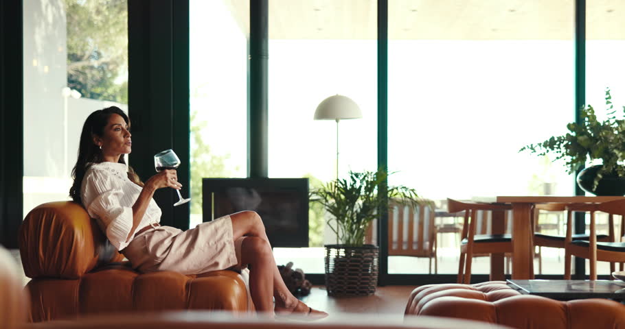 Sofa, woman and wine in home for relax, peace and calm while walking in luxury house. Alcohol glass, living room and person drink beverage, remember memory and thinking of dream on weekend break