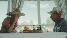 Grandfather with her grandson plays chess on the summer veranda in the garden - Powered by Shutterstock - Get 15% off with code: PIKWIZARD15