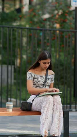 A young artist sketches outdoors in a sunlit park, creating art amidst natures beauty