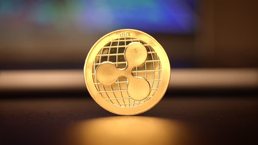 A Shiny Ripple Cryptocurrency Coin is beautifully displayed on a dark, reflective surface
