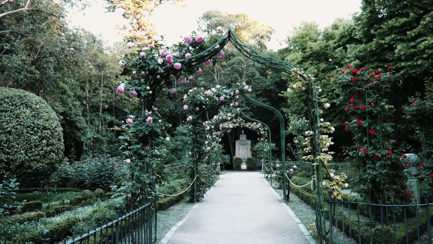 A peaceful walk through Parque Campo Grande in Valladolid, Spain, surrounded by vibrant blooming roses, lush greenery, and colorful flowers. 