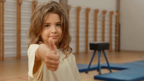Little Caucasian girl child kid student teenager showing thumb up recommend approve like gym elementary school sport lesson learning gymnasium schoolgirl gesture good finger adoption education sign - Powered by Shutterstock - Get 15% off with code: PIKWIZARD15