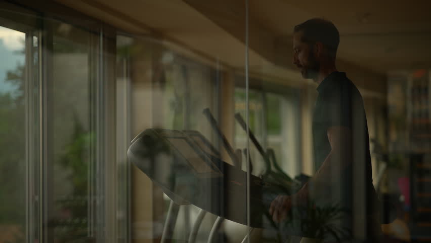 A Man Engaged in Exercising on a Treadmill Within a Contemporary Gym Environment
