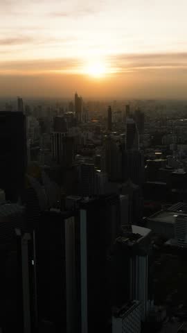 Sunset view over the city skyline with high rise buildings and scattered clouds. Bangkok, Thailand.