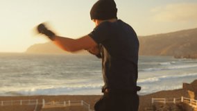 Determined sporty man practicing air boxing while overlooking the seascape, with mountains and sky at sunset. Powerful, fit young man doing interval training in nature - Powered by Shutterstock - Get 15% off with code: PIKWIZARD15