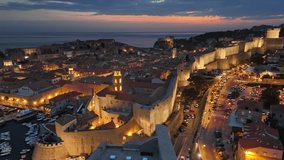 Aerial shot of historic city of Dubrovnik in Croatia, UNESCO World Heritage site. Illuminated streets, buildings and marina with boats. Dubrovnik old town after sunset with city lights. 4K HDR shot  - Powered by Shutterstock - Get 15% off with code: PIKWIZARD15