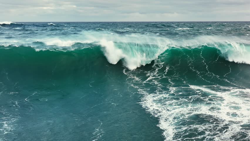 Powerful ocean waves crashing against the shore in a dramatic display of nature force. Aerial slow motion shot of sea or ocean surf