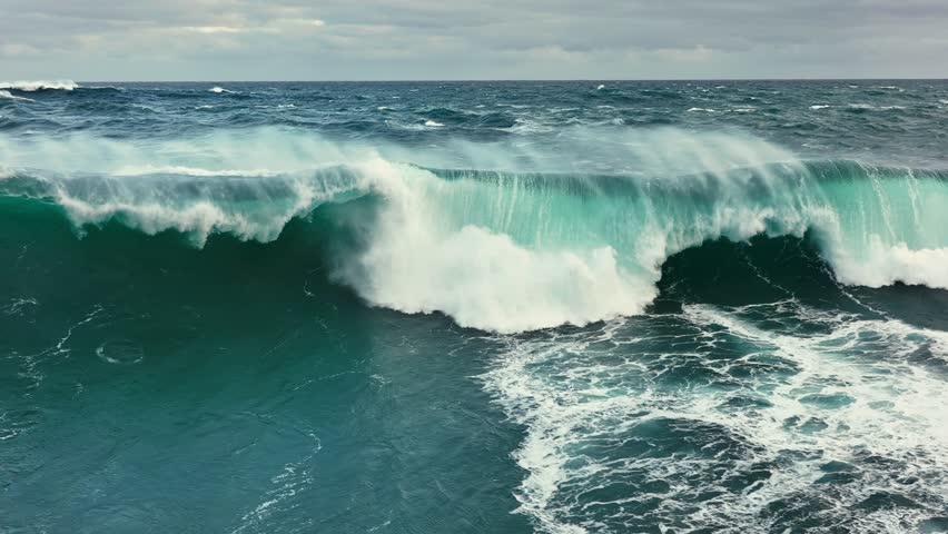 Powerful ocean waves crashing against the shore in a dramatic display of nature force. Aerial slow motion shot of sea or ocean surf