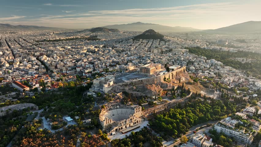 Fly over Parthenon in Athens in the morning, Ancient Greece landmark. Aerial view of Athens, Greece at sunrise, showcasing Acropolis and surrounding city. Ancient ruins are bathed in golden light 