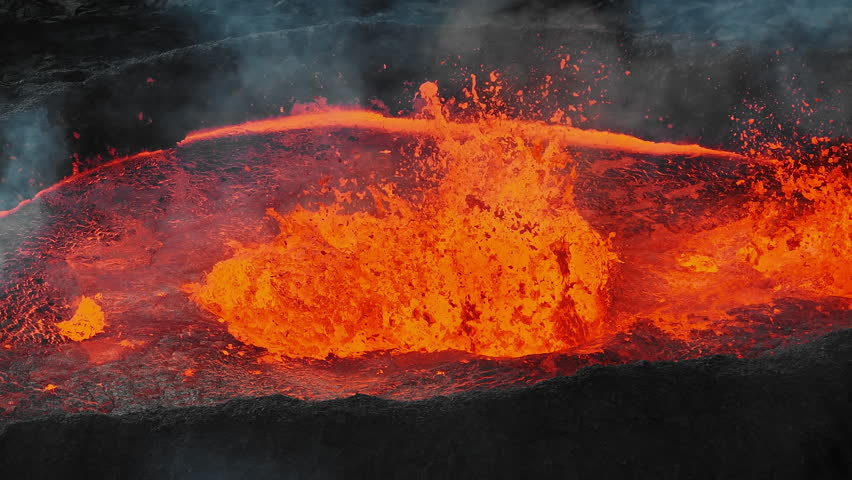 Unique close up view of red hot lava exploding, boiling, and bubbling in the volcano crater, drone shot. Volcanic eruption, natural hazard, and disaster concepts.