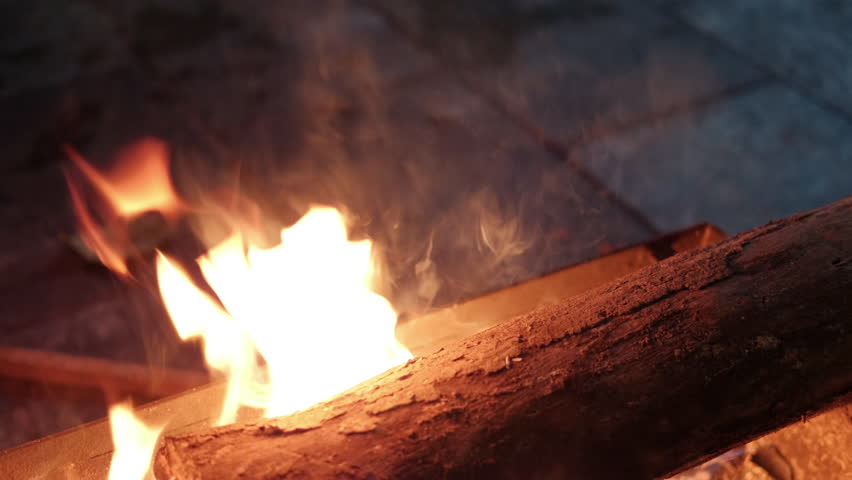 POKHARA, NEPAL - JANUARY 7, 2025: Cozy evening with a vibrant bonfire in Pokhara, Nepal, where orange and blue flames create a serene atmosphere, close up handheld shot.