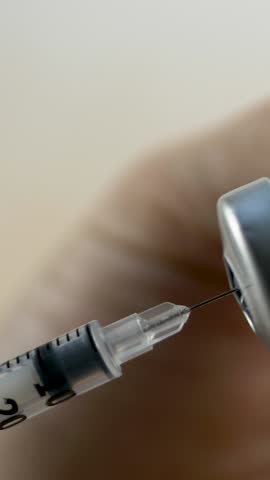 Paramedic hand steadies vial while filling syringe with liquid medication. Medical treatment preparation for effective patient care. Immunization process. Professional medical equipment use 