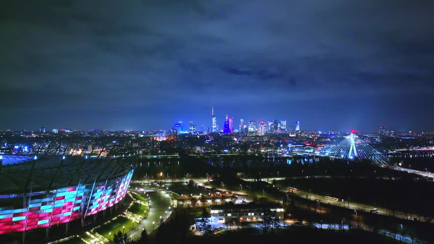 Aerial view of Warsaw’s vibrant night—Świętokrzyski Bridge, Palac Kultury, glowing roads, and a bustling city full of motion.