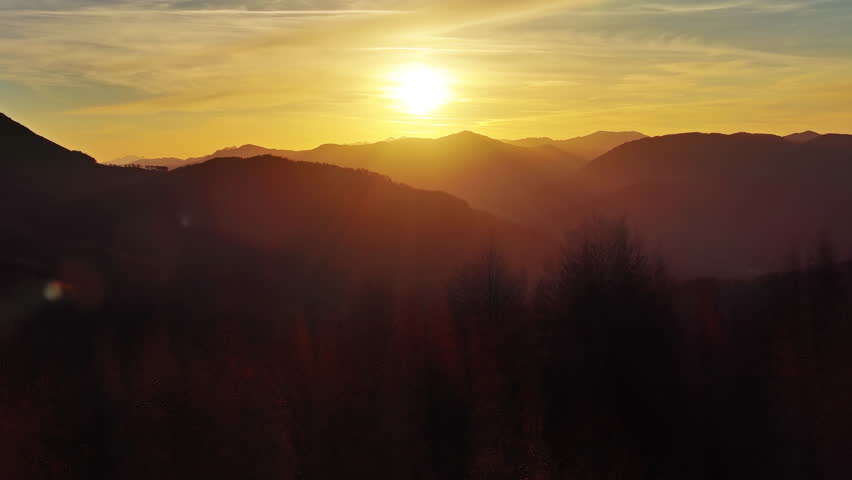 Flying over colorful foliage at sunset in mountains. Vibrant autumn landscape, 4k