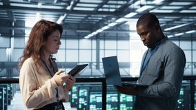 Colleagues in data center workplace use laptop to calibrate energy usage. Server farm IT specialist using notebook to inspect UPS configurations, doing maintenance on equipment, camera B - Powered by Shutterstock - Get 15% off with code: PIKWIZARD15