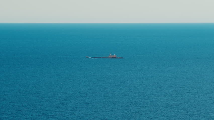 Naval submarine moving slowly on surface in the calm open blue sea