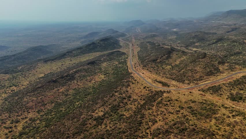 Kenyan arid landscape with winding road through hills, drone footage