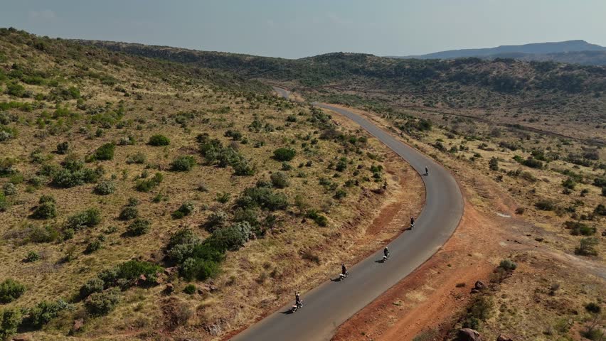Aerial view of motorcycles on a winding road in Kenya, footage from a drone