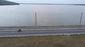 Aerial view to biker riding on modern sport motorbike at road near lake. Motorcyclist racing his motorcycle at dam route on summer day. Man drive bike during trip. Concept of freedom and adventure - Powered by Shutterstock - Get 15% off with code: PIKWIZARD15