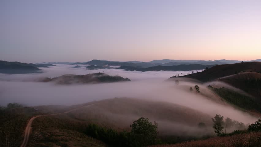 Landscape view of the sea of fog flowing on hills at dawn