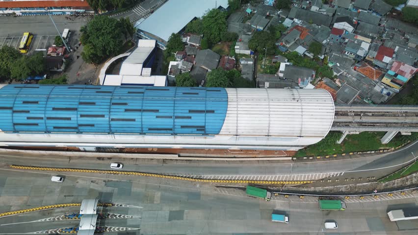 Aerial view of a Jakarta LRT station, showing the station building, surrounding neighborhood, and rail tracks.