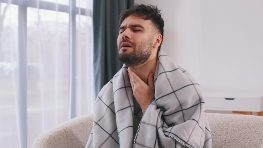 Pain in the throat. Sick man is feeling bad at home.