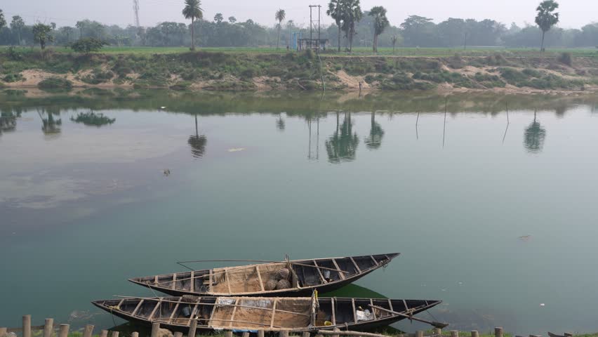 Two boats are moored by the river