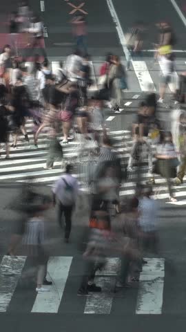 SHIBUYA, TOKYO, JAPAN : Aerial top view of Shibuya crossing in daytime. Crowd of people at the street. Japanese people, society and diversity concept video. Blurred vertical shot.