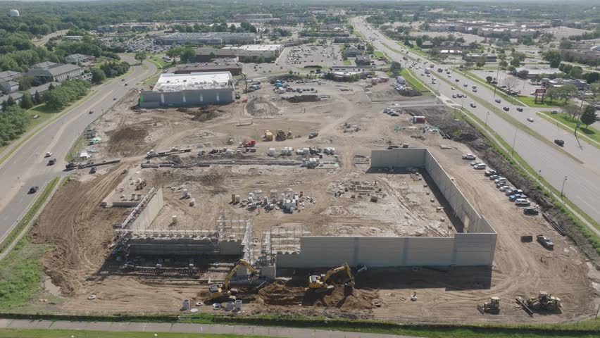 High angle aerial view of construction site during afternoon with a busy road beside it.