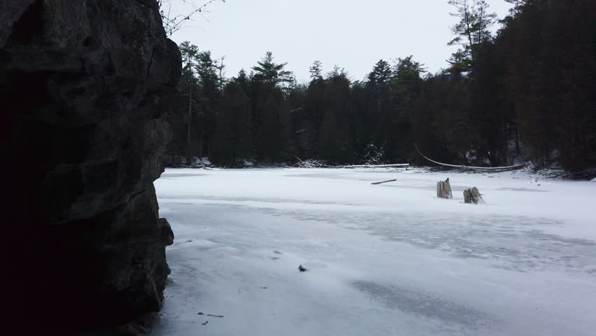 A river covered with ice in winter among the rocks against the background of a coniferous forest. The Rockwood Conservation Area, also known as Rockwood Park in Rockwood, Ontario, Canada.