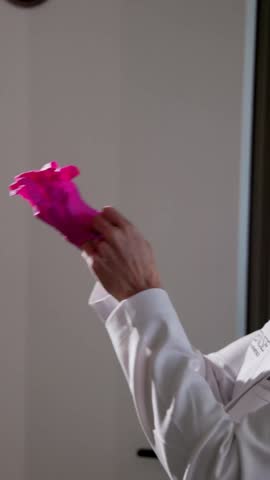 a doctor puts on pink medical gloves in dramatic lighting