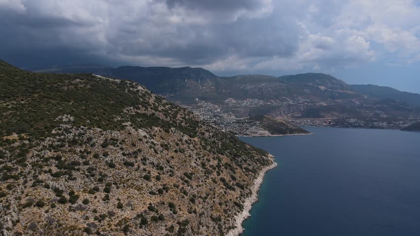 Mountain ridge along the coast of Turkey. The blue sea and beautiful mountains. Cloudy sky. View from the drone. Traveling through the coastal cities of Turkey