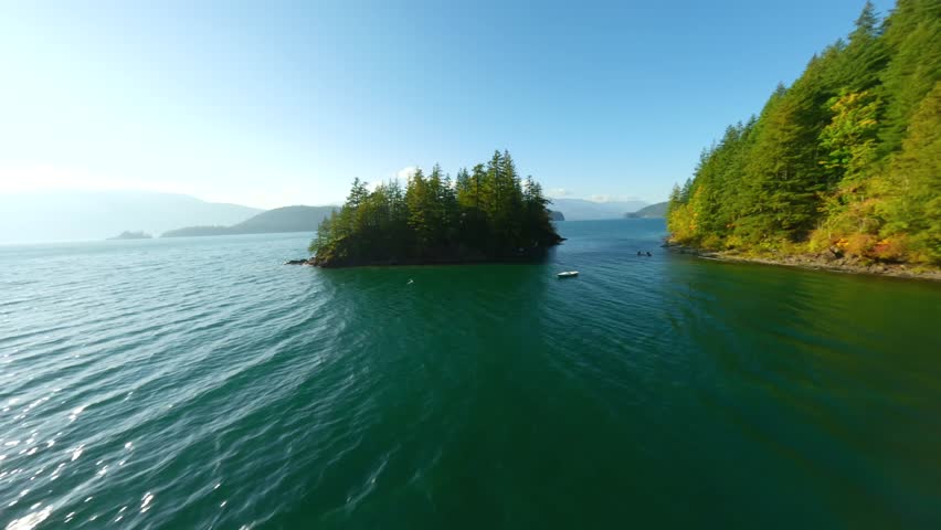 FPV Aerial view of colourful forest on mountain slopes and Harrison Lake. Canada