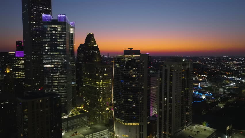 Aerial view rising toward illuminated skyscrapers, evening in Houston, USA