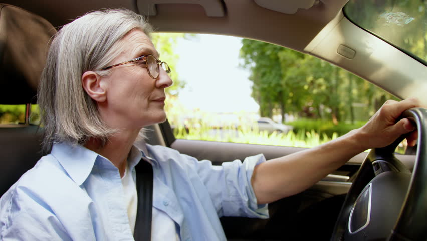 Satisfied glad smiling Caucasian senior mature female woman car owner automobile buyer driver inside vehicle auto driving turns steering wheel ride motorcar rent transportation rental service leasing